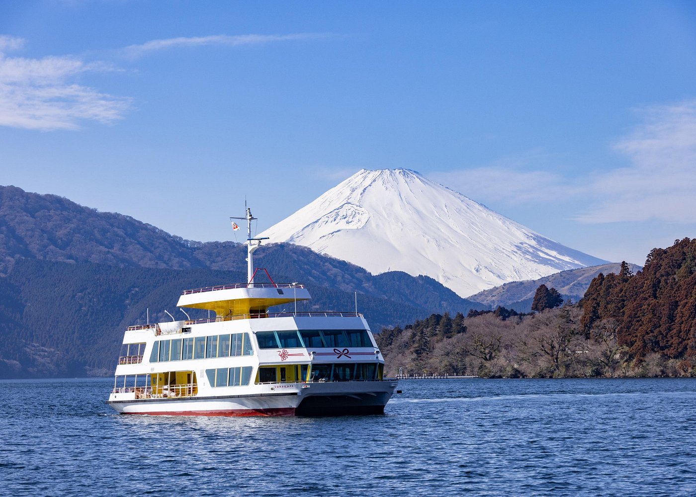 White and yellow sightseeing boat on Lake Ashi, with snow-covered Mount Fuji behind the far shore